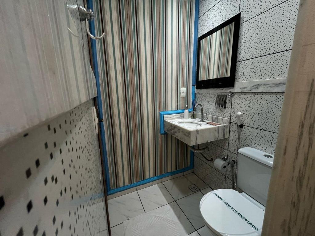 ein Badezimmer mit Toilette, Waschbecken und Spiegel in der Unterkunft casa 3 quartos1suíte com frigobar smart tv netflix ar-condicionado in Campina Grande