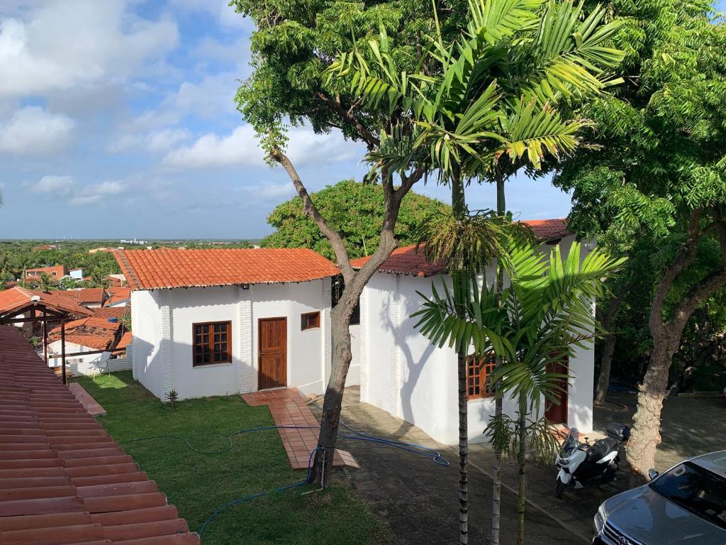 a white house with a palm tree in front of it at Chalés de Morro Branco in Beberibe