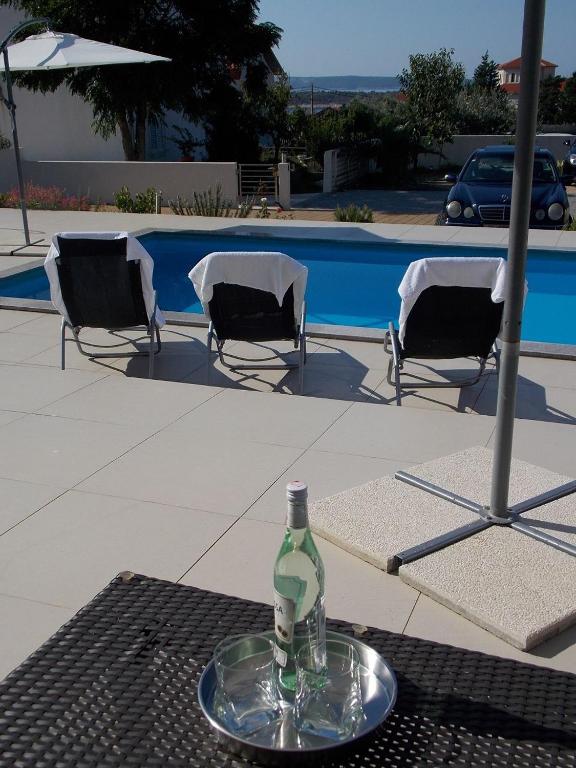 a bottle on a table with two chairs and a pool at Apartment Markle in Banjol