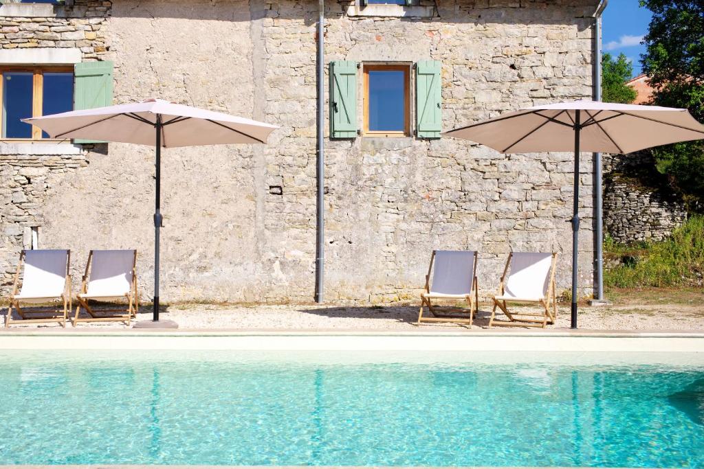 a group of chairs and umbrellas next to a pool at Maison Saint-Martin in Calvignac