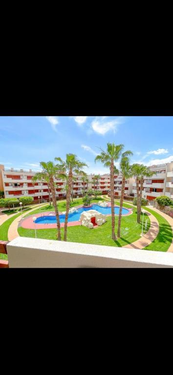 a view of a resort with a swimming pool and palm trees at El Soleado El Rincon in Campoamor
