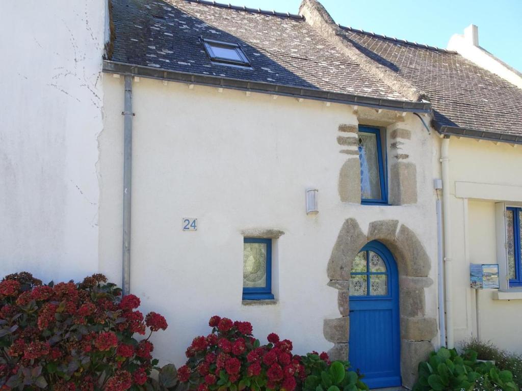 une maison blanche avec une porte bleue et des fleurs dans l'établissement Cottage in Saint-Gildas near Gulf of Morbihan, à Saint-Gildas-de-Rhuys