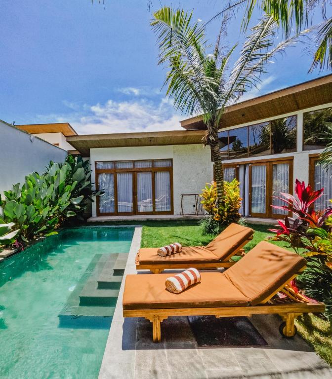 a villa with a swimming pool and two lounge chairs at Maravilla Complex in Nusa Penida