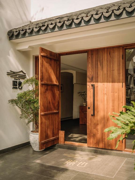 eine offene Holztür in einem Haus mit einer Pflanze in der Unterkunft Shine on in Kunshan