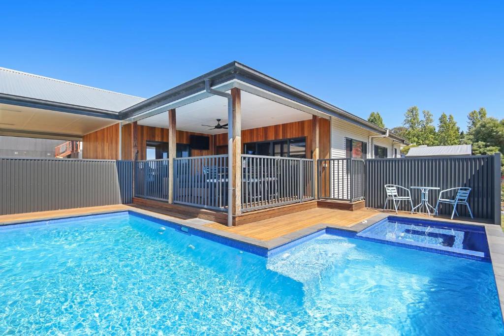 a swimming pool with a deck and a house at Newtown Falls Retreat in Beechworth