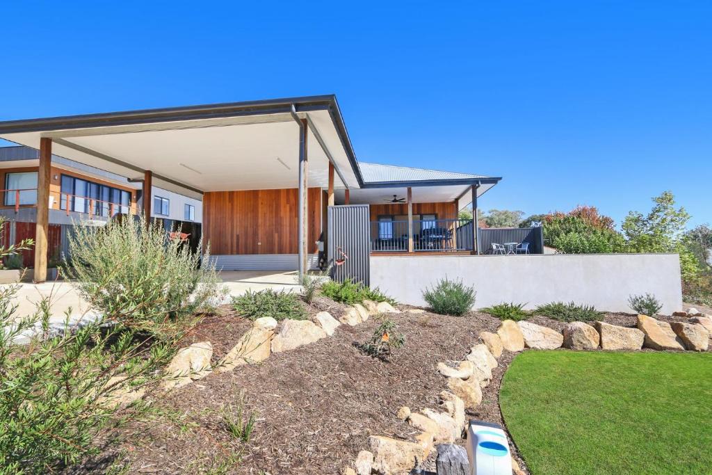 a home with a stone retaining wall and a yard at Newtown Falls Retreat in Beechworth
