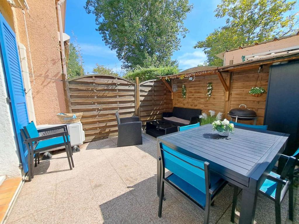 un patio avec une table, des chaises et un barbecue dans l'établissement Maison mitoyenne climatisée 7 pers. avec piscine et parking à Marseillan-Plage - FR-1-326-848, à Marseillan