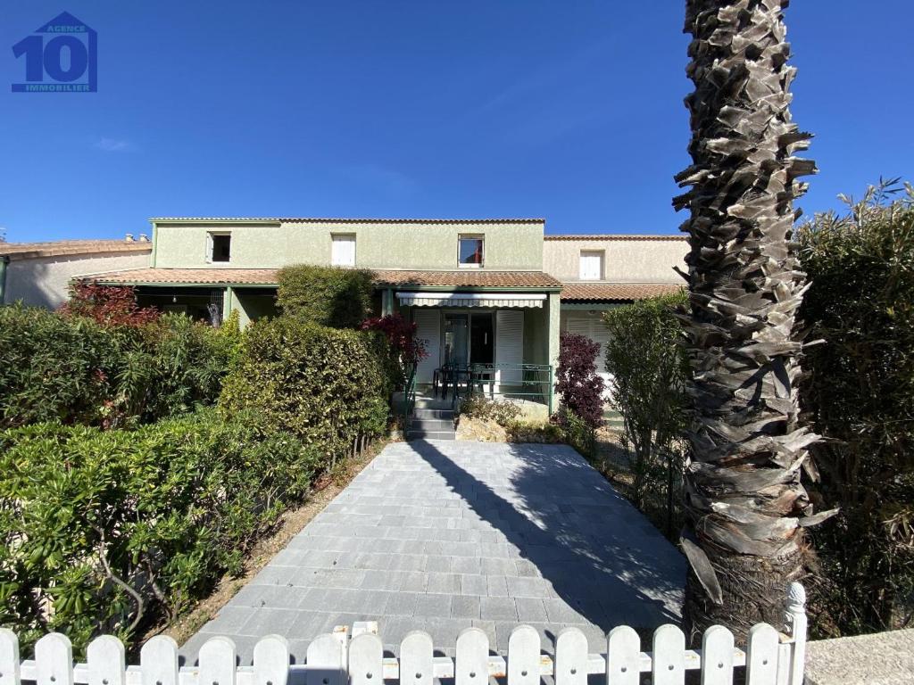 un palmier devant une maison avec une clôture dans l'établissement Pavillon à Valras-Plage, climatisation et parking, proche plage - FR-1-781-92, à Valras-Plage