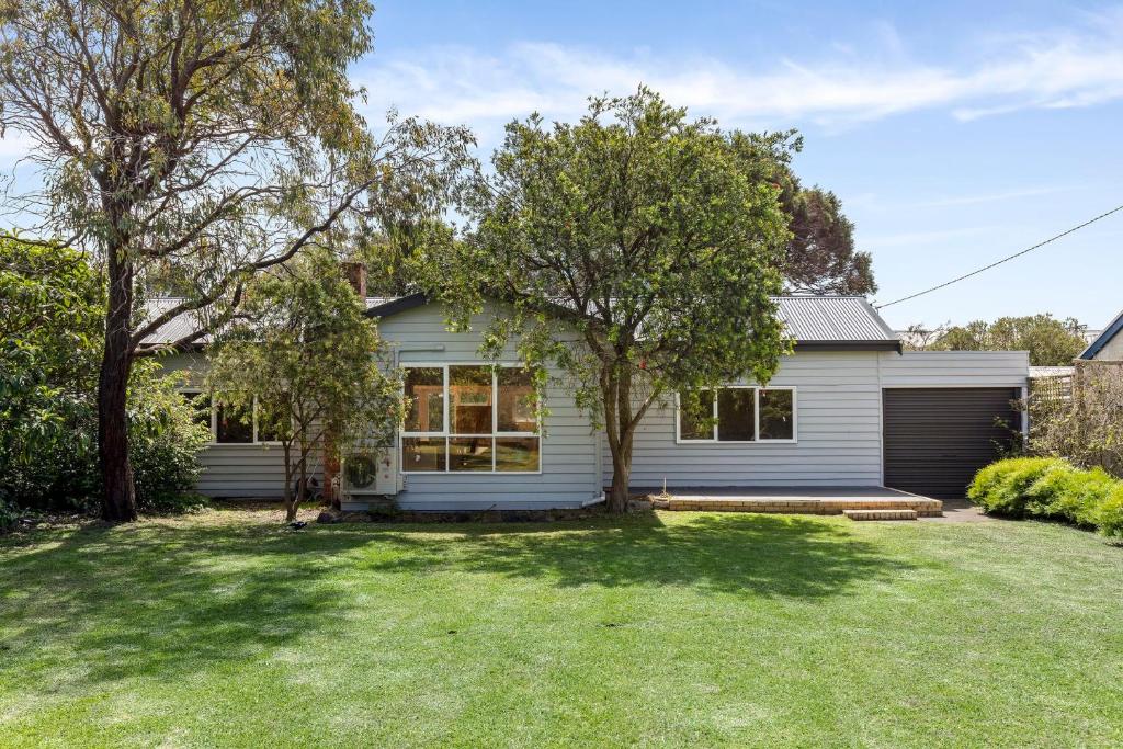 een wit huis met een boom in de tuin bij Springs Beach House in Point Lonsdale