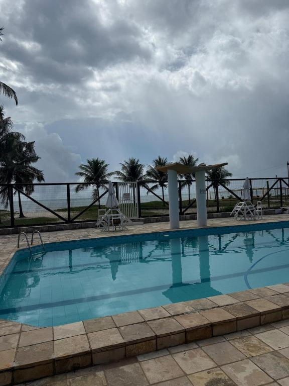a swimming pool with a view of the ocean at Apartamento pé na areia com piscinas em Guaibim in Valença