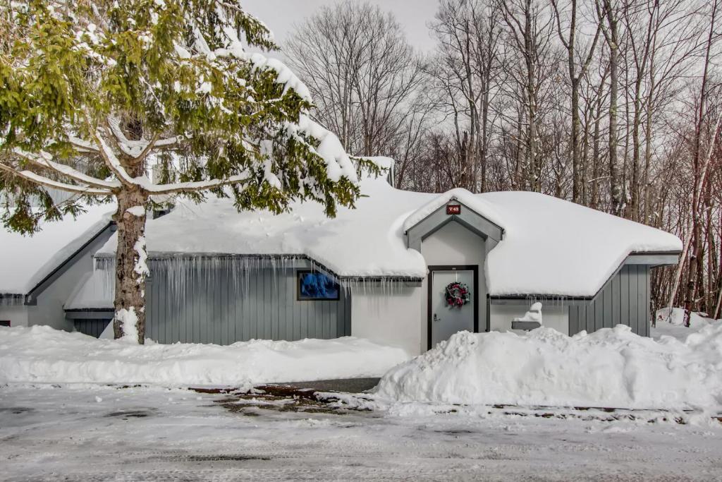 a garage covered in snow next to a tree at Woods Village 43 in Killington