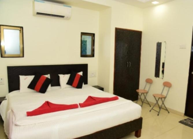 a bedroom with a large white bed with red pillows at Salil farm Resort Nagaon in Alibaug