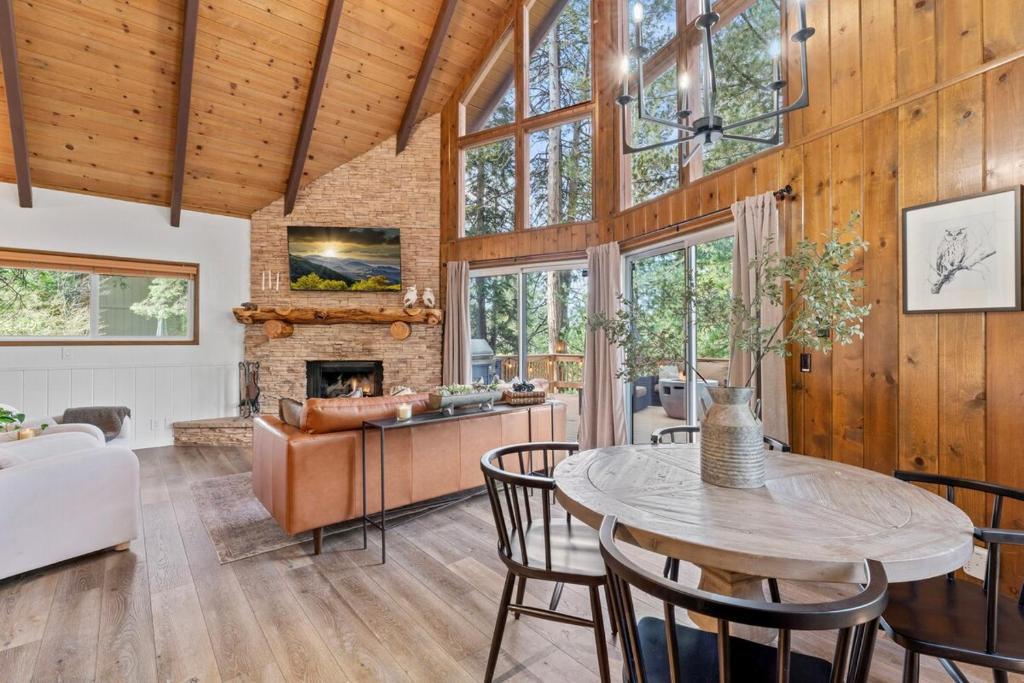 ein Wohnzimmer mit Tisch und Stühlen und einem Kamin in der Unterkunft Cozy Owl Lodge, Central AC & Hea, Spa Tub & BBQ in Lake Arrowhead