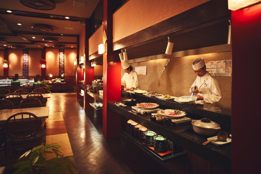 two chefs preparing food in a restaurant kitchen at ANA InterContinental Manza Beach Resort by IHG in Onna