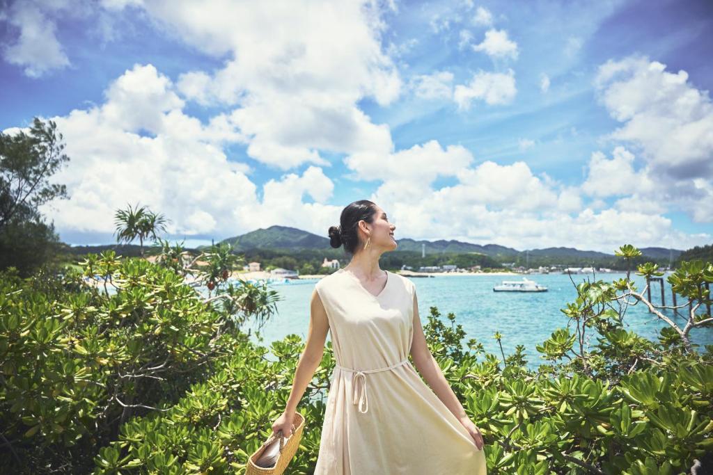 a woman in a white dress standing by the water at ANA InterContinental Manza Beach Resort by IHG in Onna