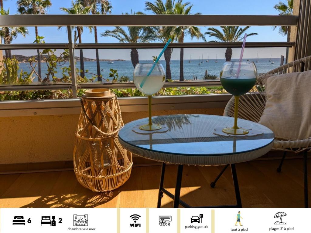 two wine glasses sitting on a table in front of a window at "Le palmier doré", cosy T3 à 3 minutes à pied des plages, parking et clim in Sanary-sur-Mer