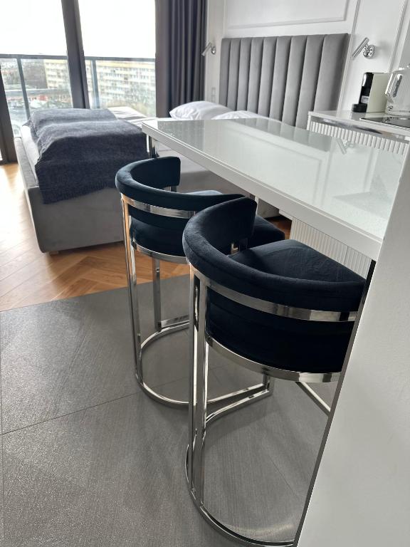 a white table with two blue chairs in a room at Hanza Tower Apartments Premium in Szczecin