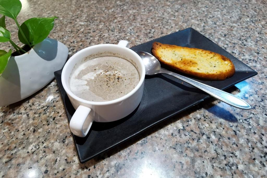 A hot coffee and toasted bread served on a black tray.