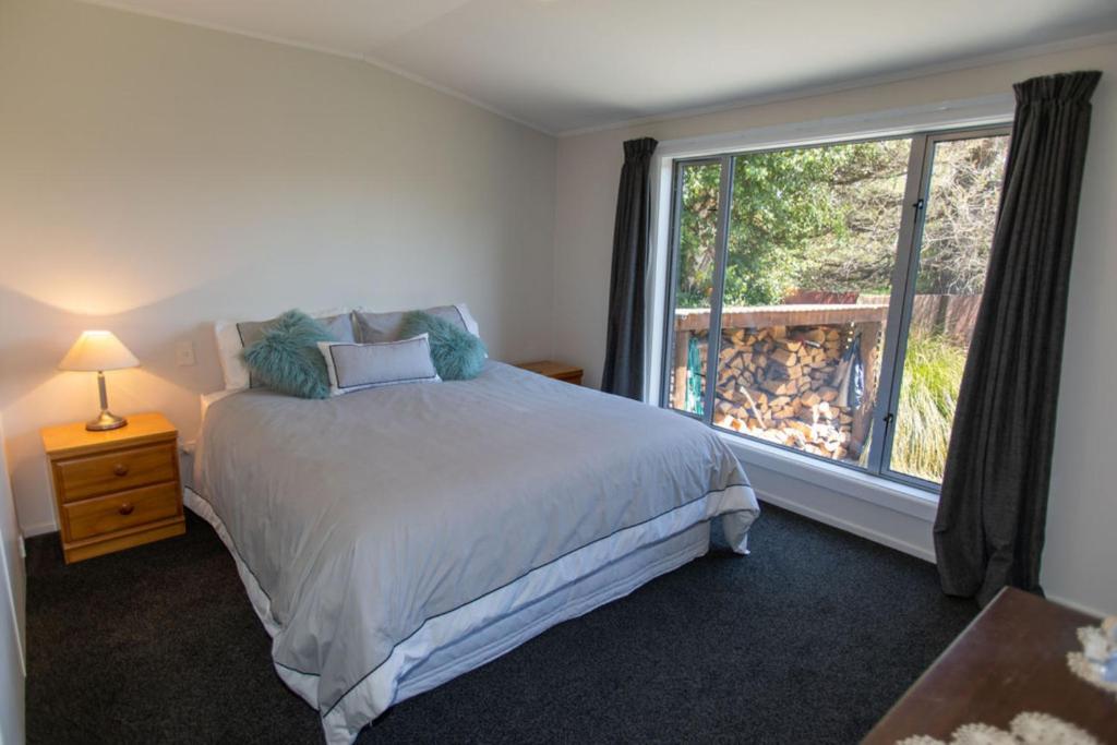 a bedroom with a bed and a large window at Private Rooms with Shared Bathroom in Lake Tekapo