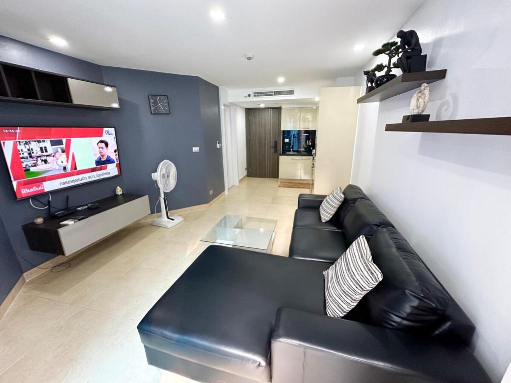 a living room with a black leather couch and a flat screen tv at Large luxury condo - Pattaya City Centre - Centara Avenue, Pool View - 217 in Pattaya Central
