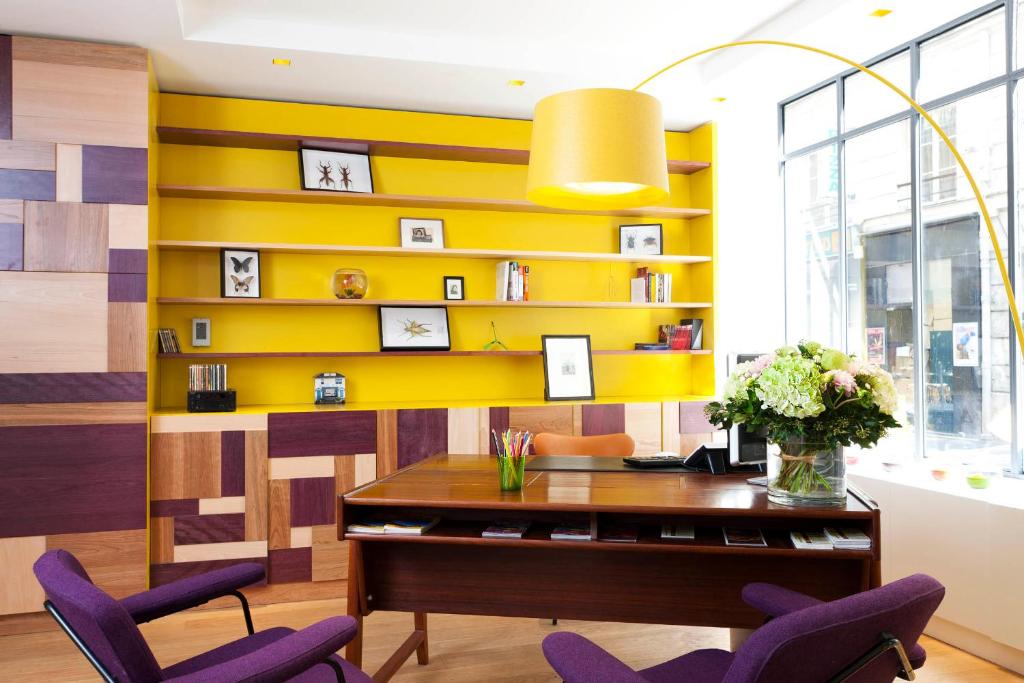 a yellow wall in an office with purple chairs at Hôtel Crayon in Paris