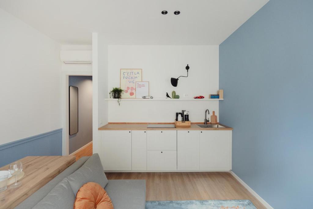 a kitchen with white cabinets and a gray couch at Bilo e Mono a 2 passi dall'Ospedale, Centro e Stazione - CasaP17 in Varese
