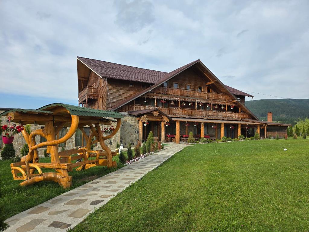 een groot houten gebouw met een groen gazon ervoor bij Poiana Bucovineana in Poiana Negrii