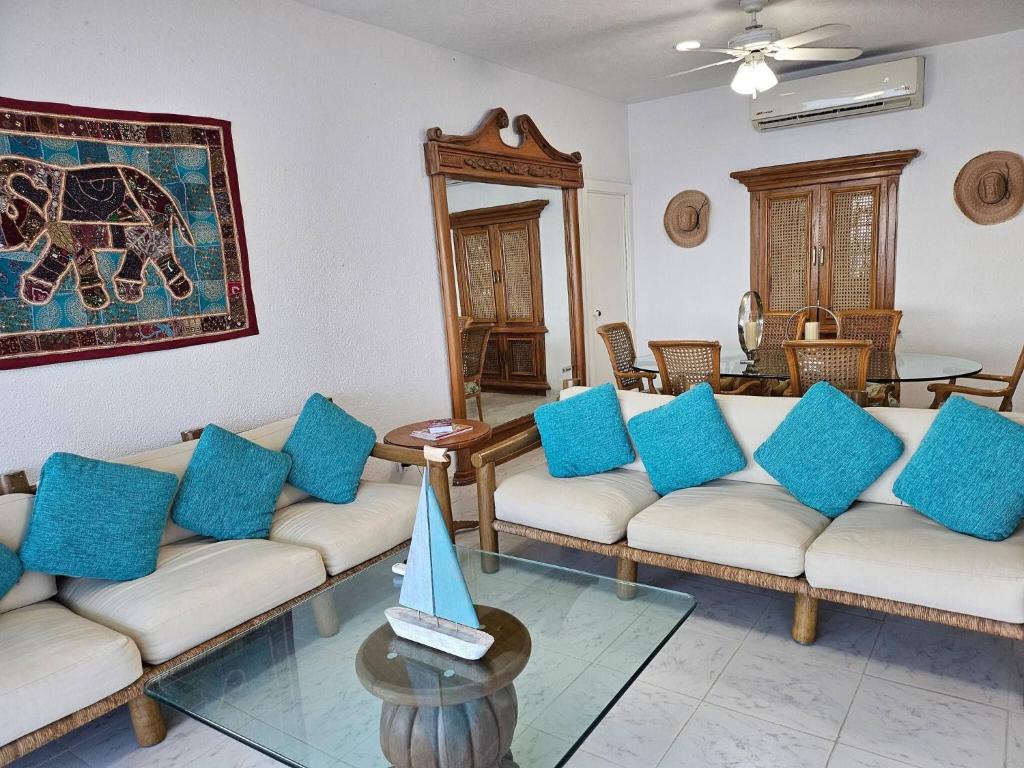 a living room with white couches and blue pillows at Tropical Paradise Getaway in Acapulco with Private Infinity Pool in Acapulco