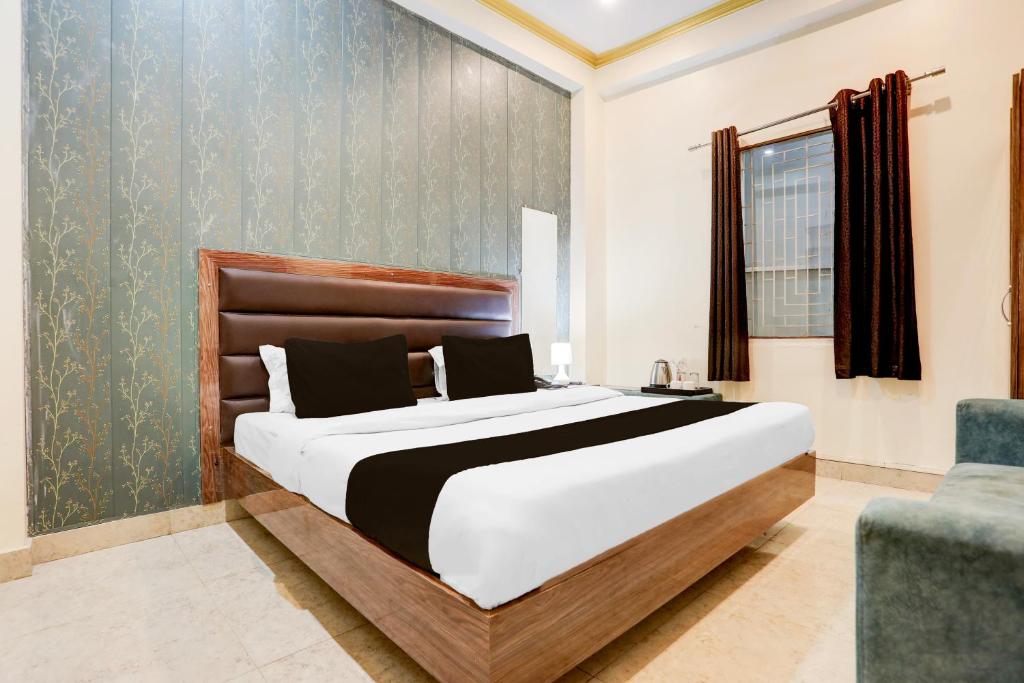 a bedroom with a large bed and a chair at Super Hotel O Sankat Mochan Gandhi Nagar in Varanasi