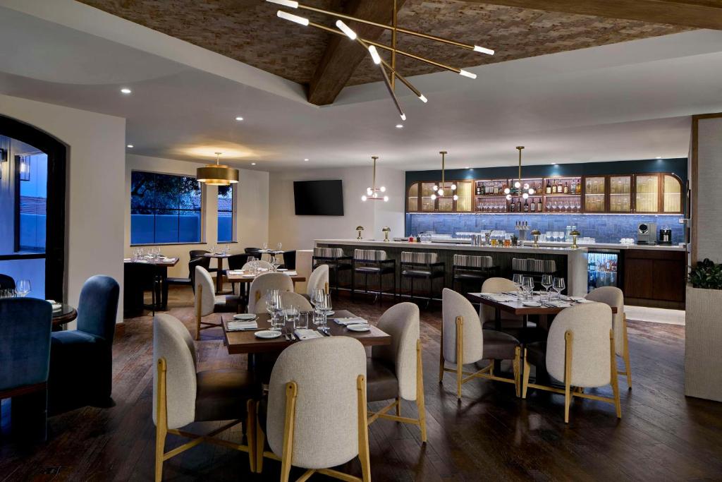 佩索罗伯斯Bellasera Hotel & Suites Paso Robles, Tapestry by Hilton的有桌椅和酒吧的餐厅