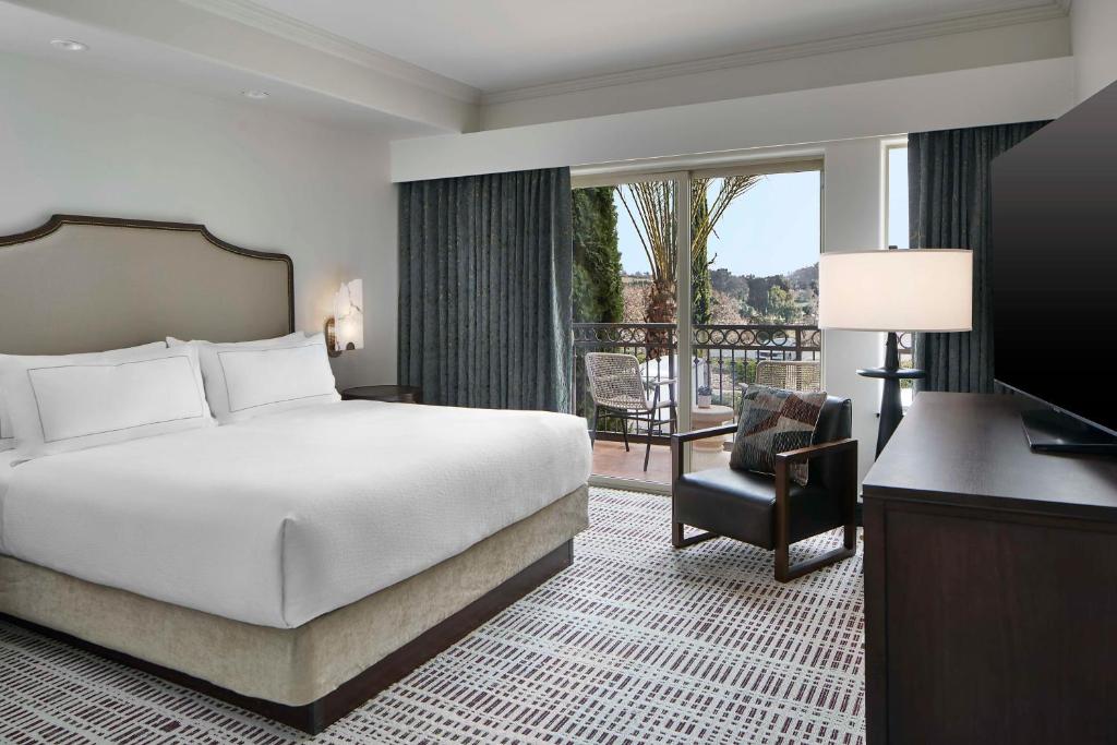 佩索罗伯斯Bellasera Hotel & Suites Paso Robles, Tapestry by Hilton的酒店客房设有一张床和一个阳台。