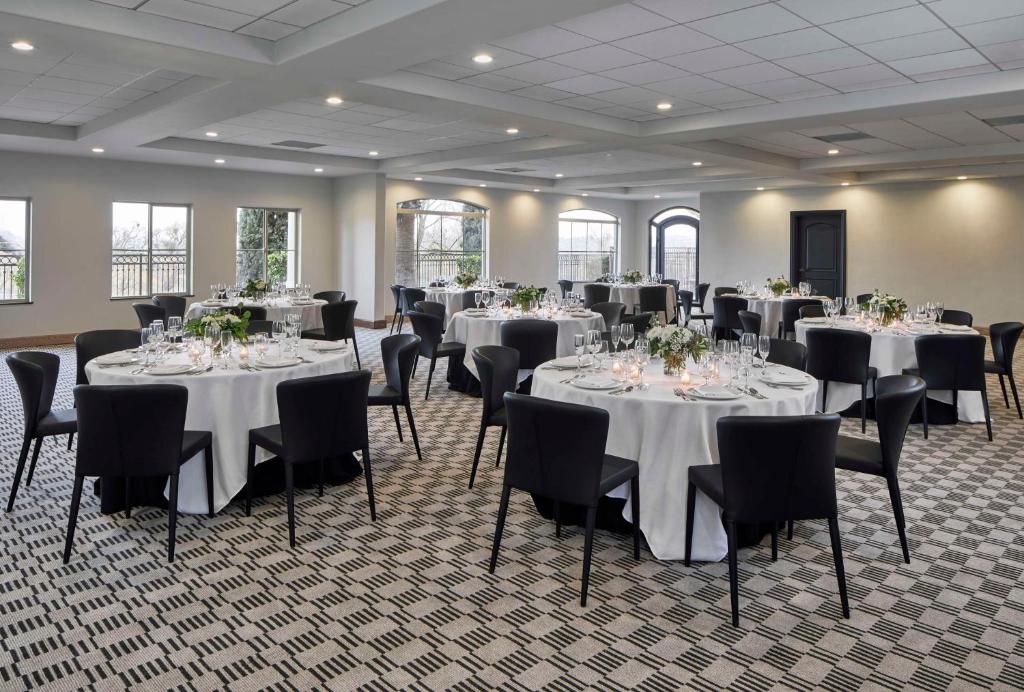 佩索罗伯斯Bellasera Hotel & Suites Paso Robles, Tapestry by Hilton的大房间设有桌椅和白色的桌布