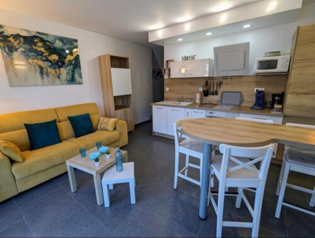 Una sala de estar con un sofá y una mesa y una cocina. en Appartement cosy mer, en Le Grau-du-Roi