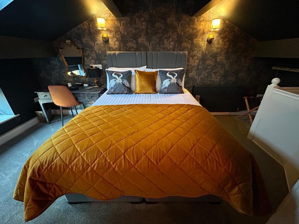 a bedroom with a bed with an orange bedspread at Aiskew Villa Annex in Bedale