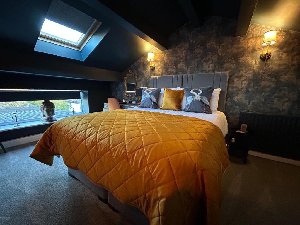 a bedroom with a bed with a yellow comforter and a window at Aiskew Villa Annex in Bedale