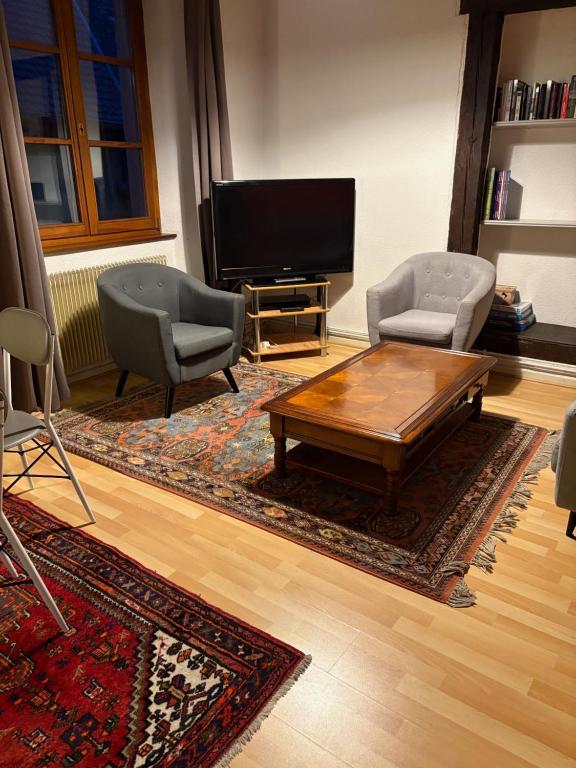 un salon avec deux chaises et une télévision dans l'établissement Appartement authentique centre historique, à Colmar