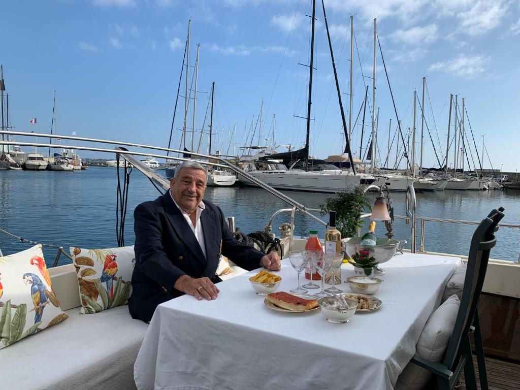 een oudere man aan een tafel op een boot bij Master Cabin in Golfe Juan in Vallauris