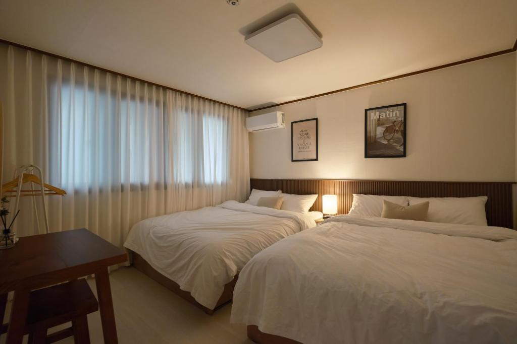 une chambre d'hôtel avec deux lits, un bureau et une fenêtre dans l'établissement Walking Distance to Sindorim Station, 3 Rooms, 4 Queen Beds, 2 Bathrooms, 1 Minute to Yeongdeungpo Station Bus Stop, à Séoul