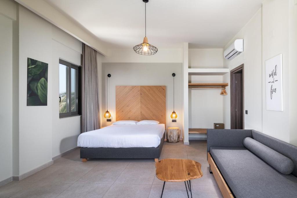 a bedroom with a bed and a couch at Malena Hotel & Suites - Adults Only by Omilos Hotels in Amoudara Herakliou