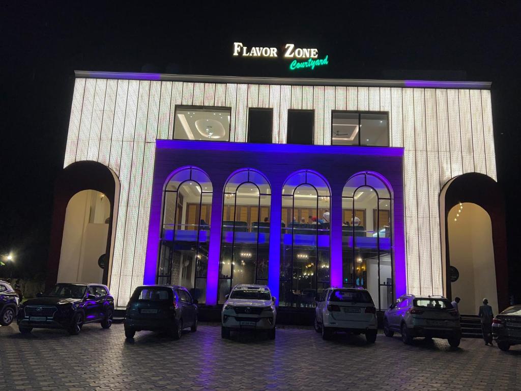 a building with cars parked in front of it at night at Flavour Zone Courtyard in Ambāla