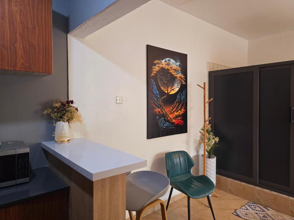 a kitchen with a counter and two chairs and a painting at MAC Homes Blueberry Suite 2 in Accra