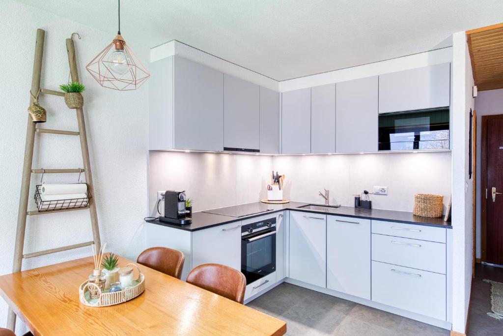 a kitchen with white cabinets and a wooden table at Val Air F75, Peace & Panoramic Views in Champéry