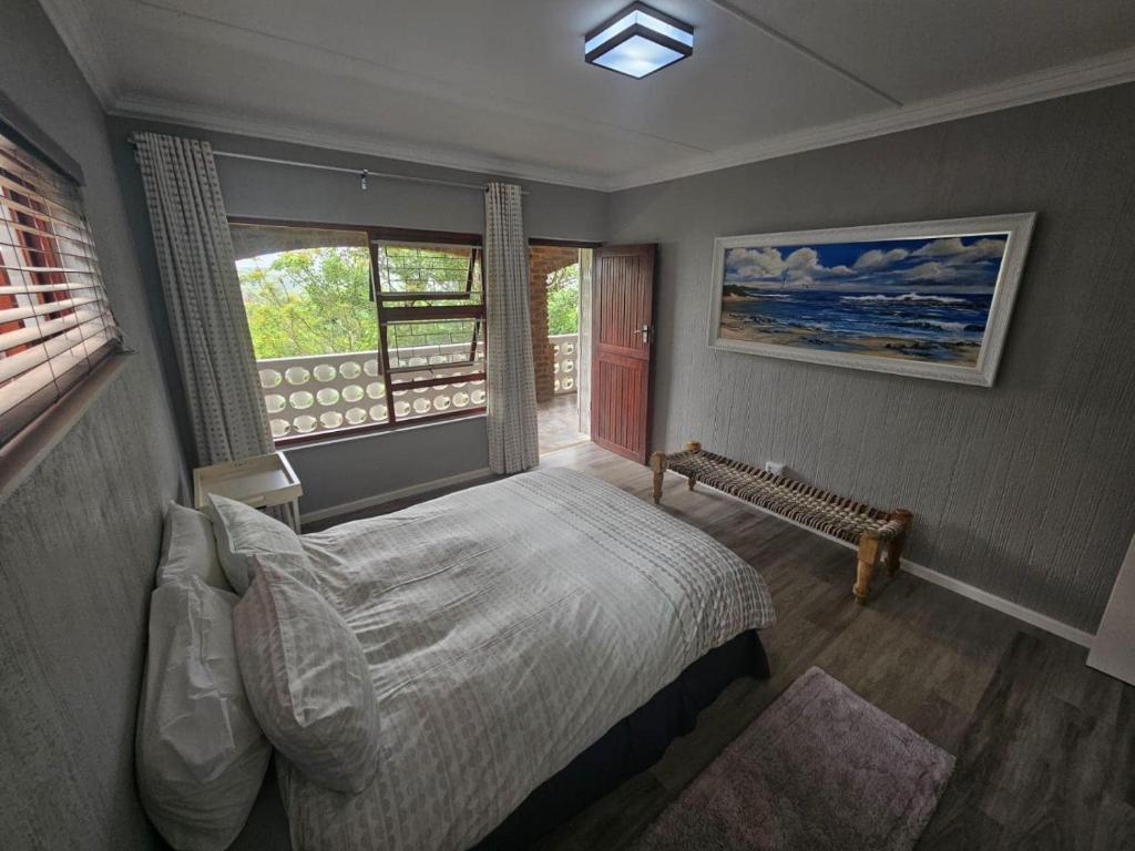 Un dormitorio con una cama grande y una ventana. en Barefoot Self-Catering Holiday Home, en Morganʼs Bay