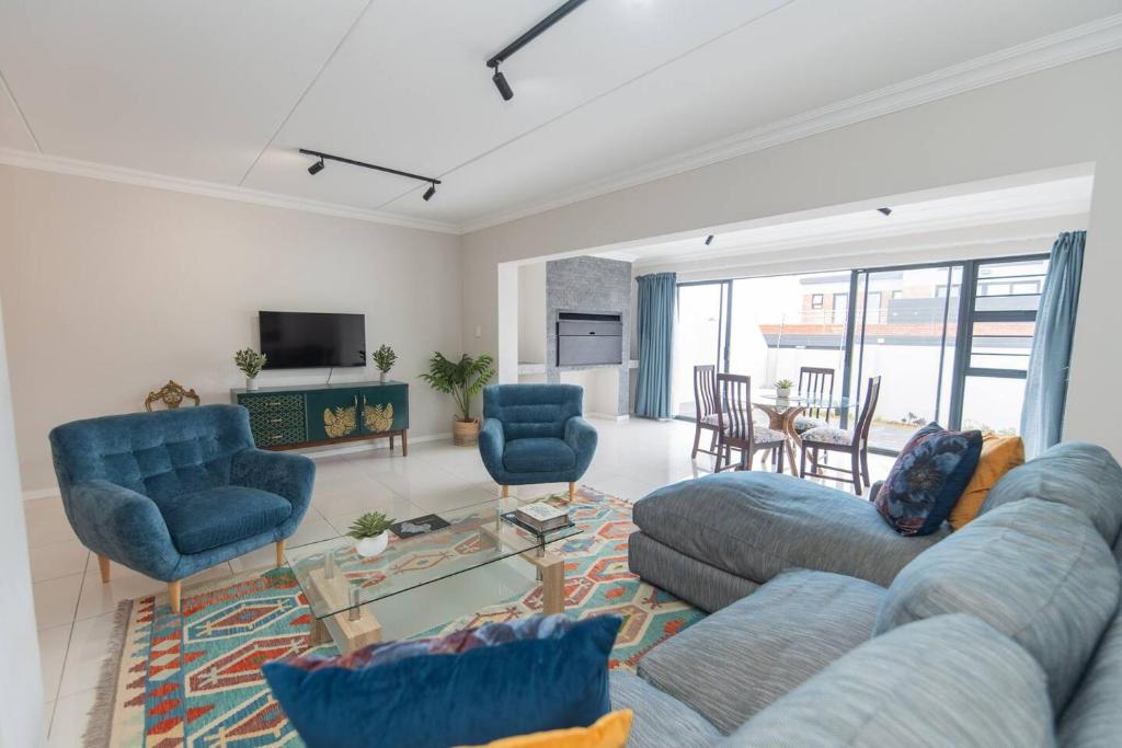 een woonkamer met een bank, stoelen en een tafel bij The Sapphire in Gqeberha