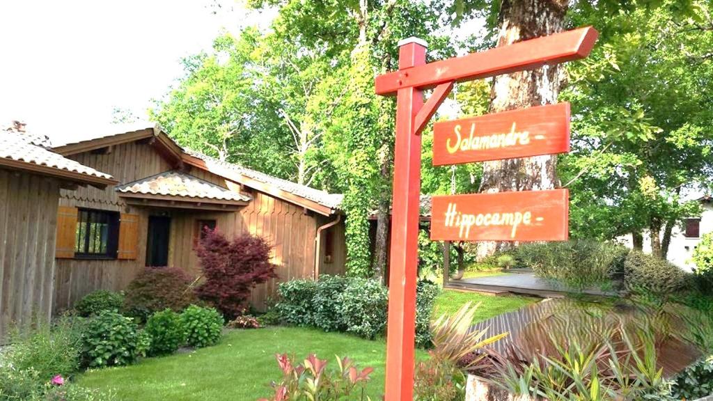 un panneau rouge dans une cour devant une maison dans l'établissement Salamandre et Hippocampe, à Lanton