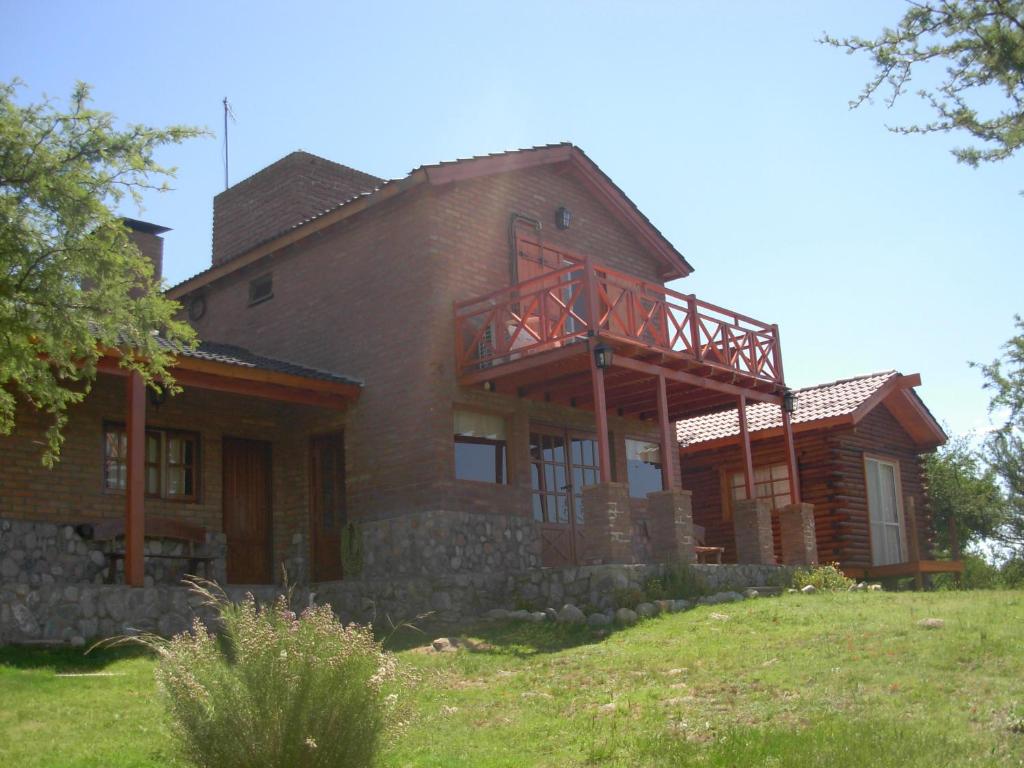 a large wooden house on a grassy hill at Complejo Arlington Village in Cortaderas