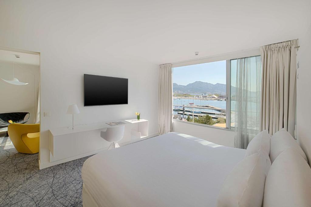 a white bedroom with a large bed and a window at nhow Marseille in Marseille