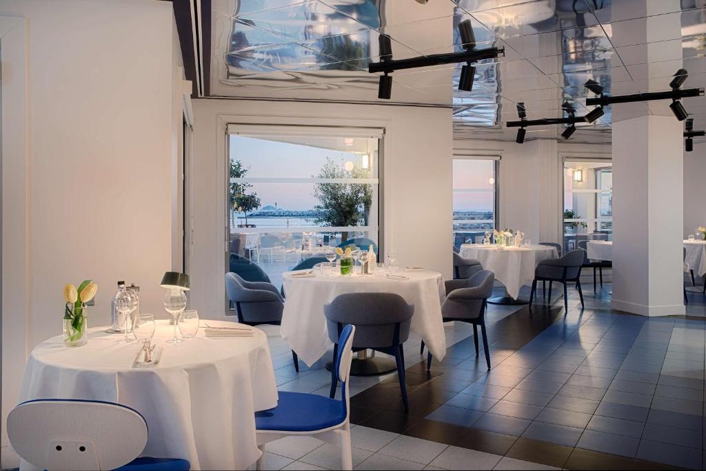 a restaurant with white tables and chairs and a window at nhow Marseille in Marseille