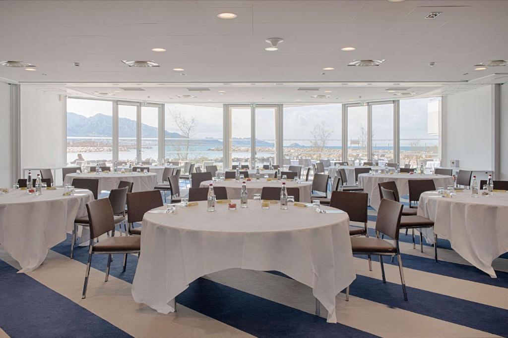 a room with white tables and chairs and windows at nhow Marseille in Marseille