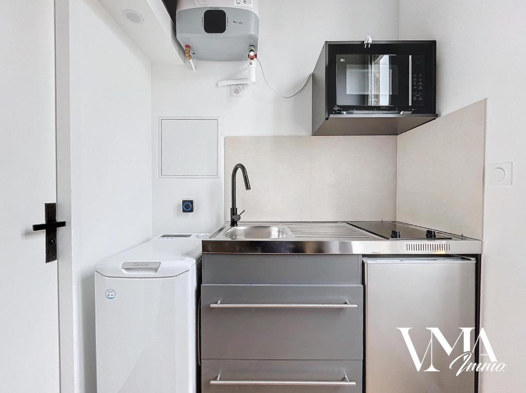 une petite cuisine avec un évier et un micro-ondes dans l'établissement Appart chaleureux gare Oullins 1, à Oullins